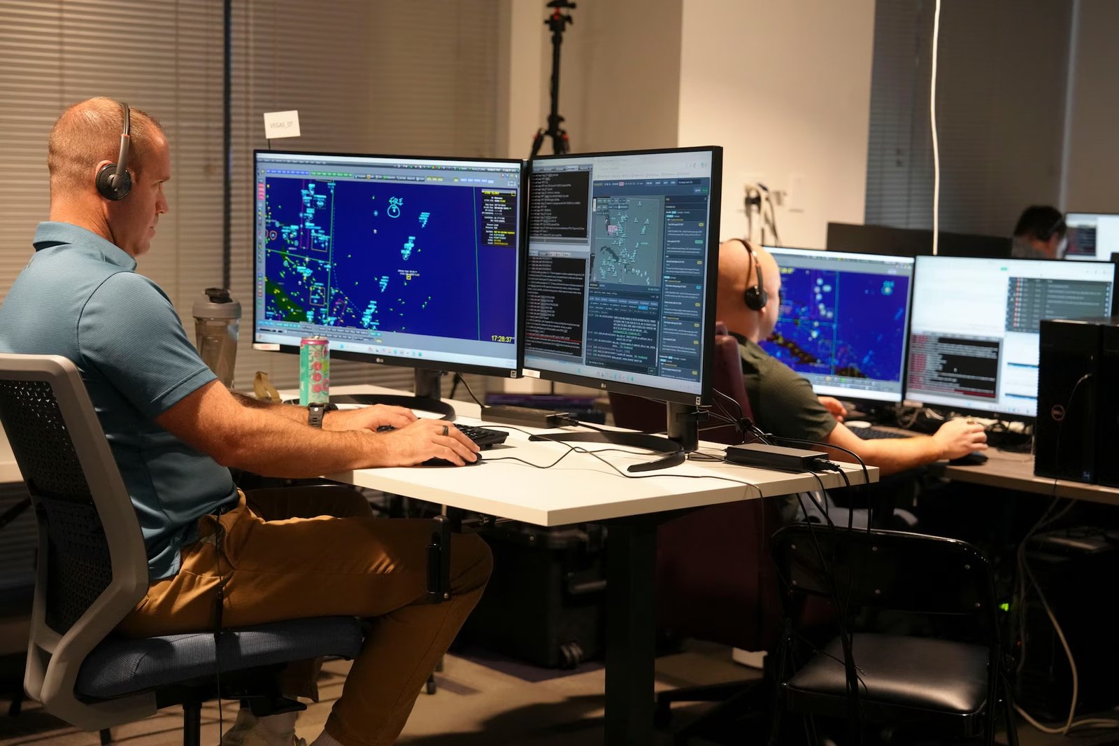 Dos participantes con auriculares utilizan aplicaciones de mando y control frente a varios monitores durante DASH.