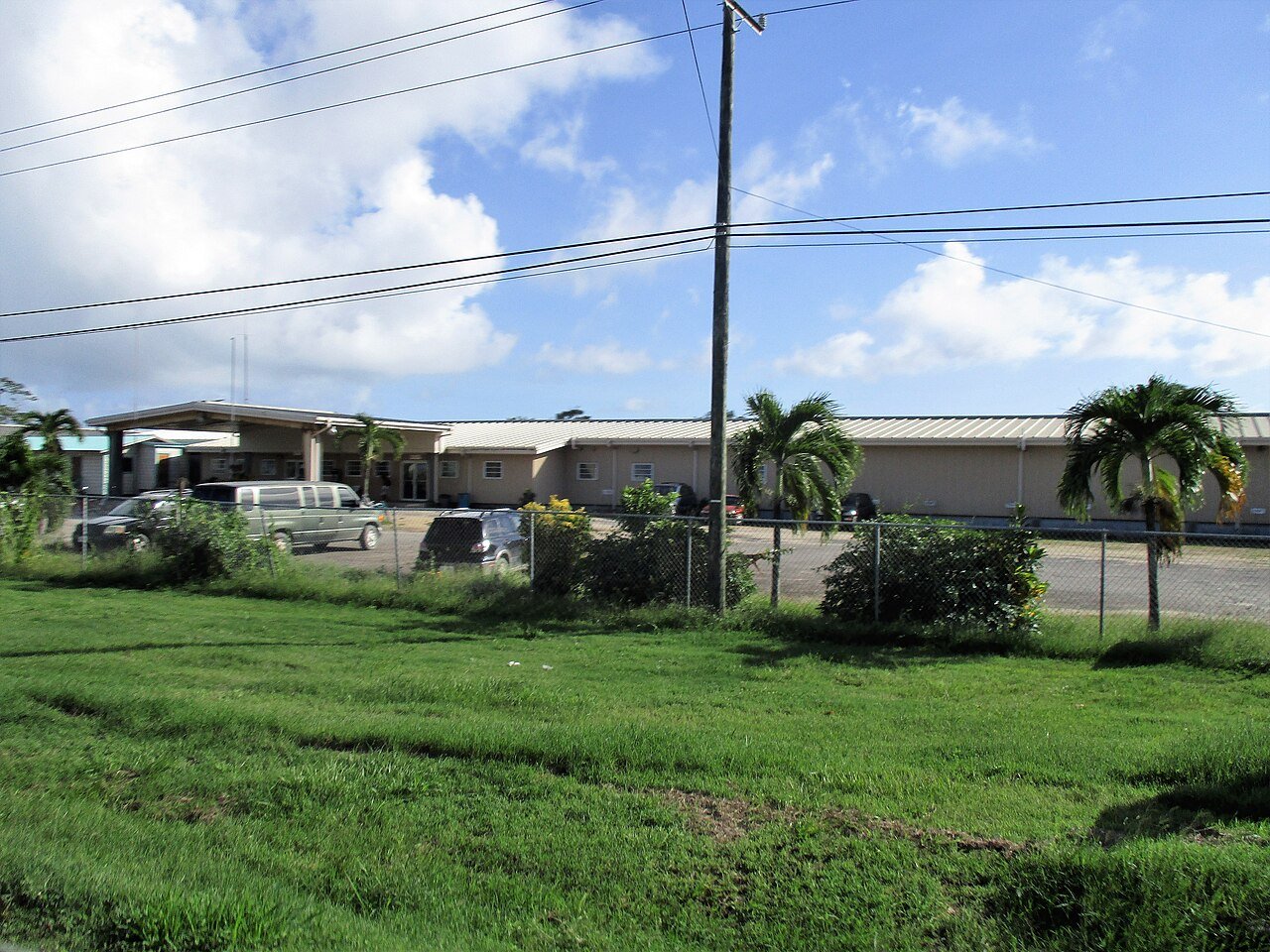 Exterior del Hospital Regional del Sur en Dangriga, Belice, con vehículos y palmeras, en noviembre de 2015.